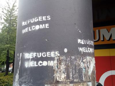 Graffiti placed by a vandal on a pole stating that refugees are welcome in the city of Groningen.