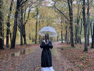 Staff member Samantha Likonde stands in a forest holding an umbrella
